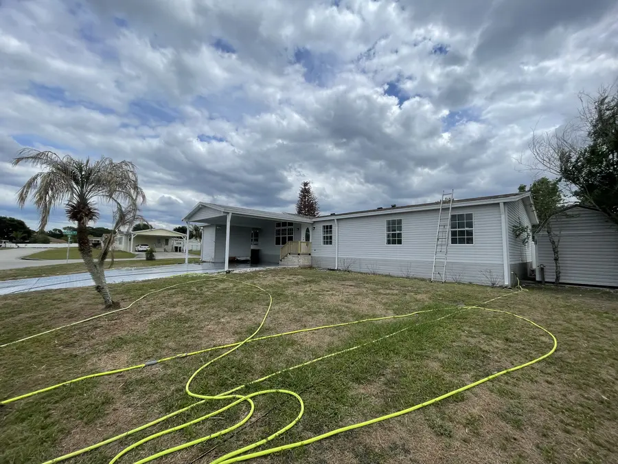 Mobile home exterior during soft wash — hose and equipment on site, Polk County FL